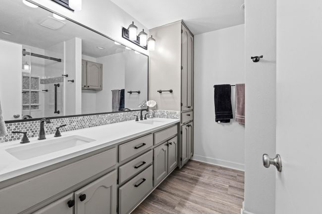 Bathroom featuring a sink, double vanity, a stall shower, baseboards, and wood finished floors | Image 22