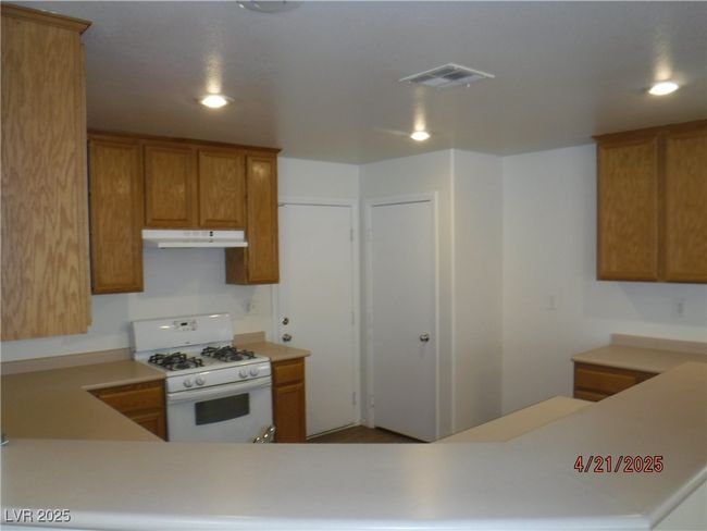 Kitchen featuring recessed lighting, visible vents, white gas range oven, and under cabinet range hood | Image 7