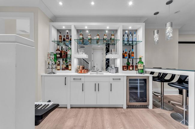 Bar featuring a sink, wet bar, light wood-style floors, pendant lighting, and beverage cooler | Image 19