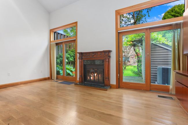 Unfurnished living room with plenty of natural light, light wood finished floors, a high ceiling, and a fireplace | Image 20