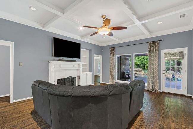 Living area featuring a ceiling fan, coffered ceiling, dark wood-type flooring, a tile fireplace, and beamed ceiling | Image 9