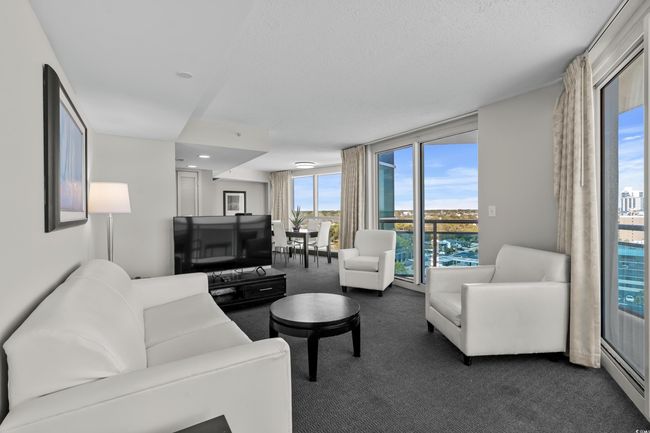 Living room featuring dark carpet, a textured ceiling, floor to ceiling windows, and baseboard heating | Image 7