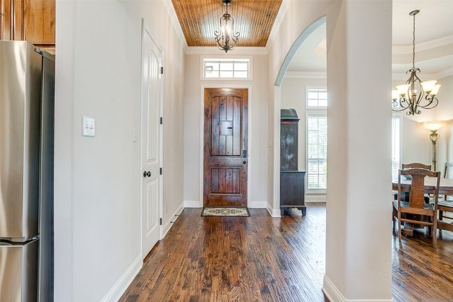 Entryway featuring crown molding, arched walkways, a chandelier, and dark wood-type flooring | Image 5