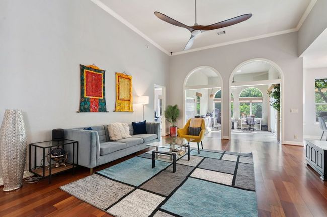 Living room featuring a towering ceiling, wood finished floors, visible vents, ornamental molding, and ceiling fan | Image 6