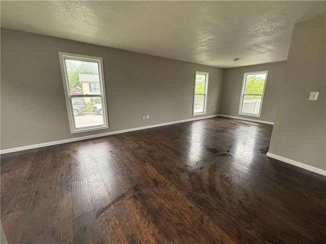 Unfurnished room with a textured ceiling, baseboards, and dark wood finished floors | Image 7