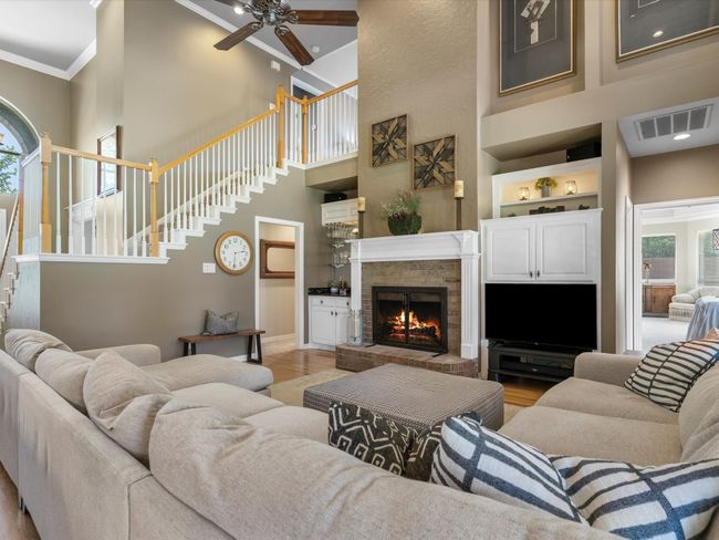Living area featuring a towering ceiling, ornamental molding, stairway, a ceiling fan, and light wood-style flooring | Image 16