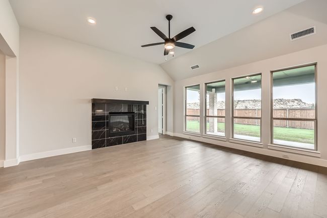 Unfurnished living room with baseboards, lofted ceiling, ceiling fan, and visible vents | Image 7