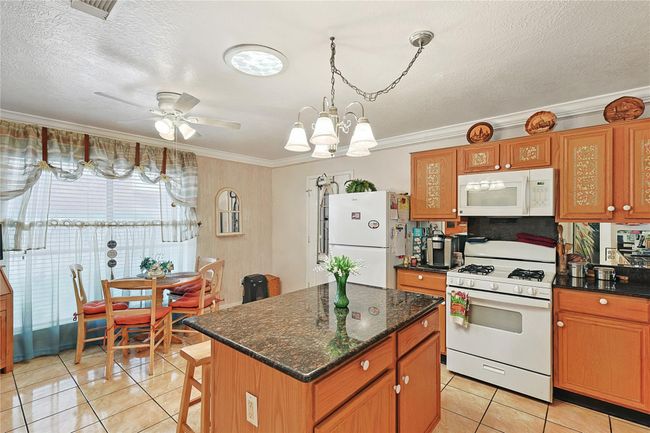 Spacious kitchen with center island, breakfast area, and skylight — filling the space with natural light. Features abundant cabinet storage and open flow to the living area, perfect for cooking and entertaining. | Image 7