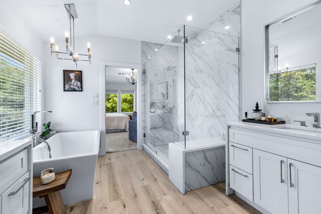Ensuite bathroom with a chandelier, a marble finish shower, a freestanding tub, vanity, and lofted ceiling | Image 24