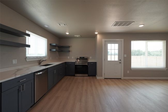 Kitchen featuring open shelves, stainless steel appliances, light wood-type flooring, and plenty of natural light | Image 11