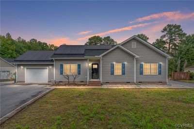 Ranch-style house with a yard, a garage, and solar panels | Image 1