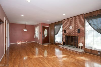 Foyer entrance with a brick fireplace, hardwood / wood-style flooring, and wood walls | Image 2