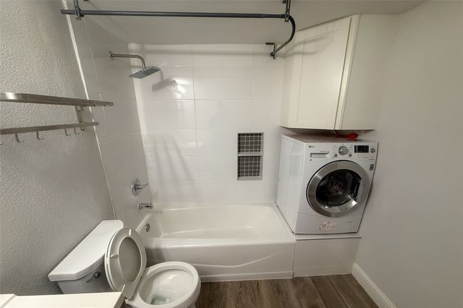 Bathroom featuring washer / dryer, wood finished floors, and shower combination | Image 9