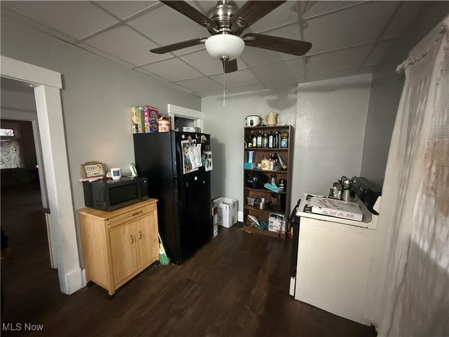 Kitchen with black appliances, dark wood-style flooring, a drop ceiling, and ceiling fan | Image 13