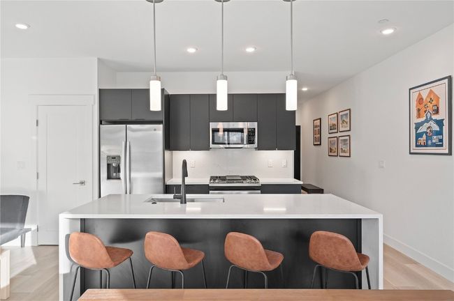 Kitchen with sink, stainless steel appliances, light hardwood / wood-style flooring, decorative light fixtures, and a kitchen bar | Image 6
