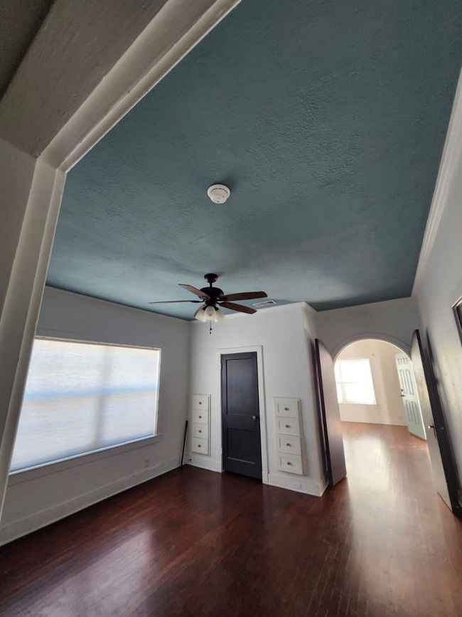 Unfurnished living room with arched walkways, wood finished floors, ceiling fan, and a textured ceiling | Image 7