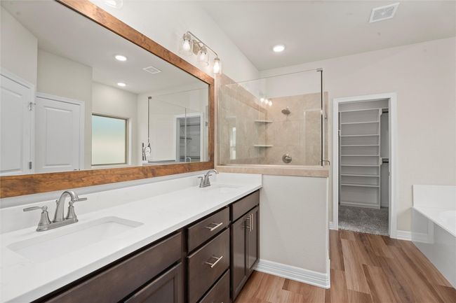 Bathroom with double vanity, a spacious closet, wood finished floors, a garden tub, and a tile shower | Image 18