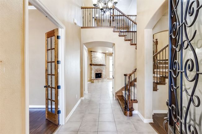 Foyer entrance with baseboards, stairs, arched walkways, a high ceiling, and a notable chandelier | Image 5