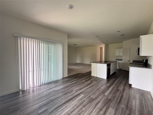 Kitchen with open floor plan, dark countertops, dark wood finished floors, and an island with sink | Image 10