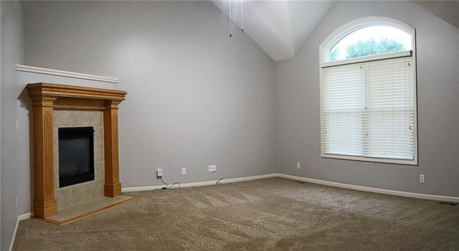 Unfurnished living room featuring carpet, a tile fireplace, vaulted ceiling, and a ceiling fan | Image 4
