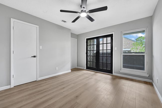 This upstairs bedroom offers a bright and airy feel with modern finishes, including luxury vinyl plank flooring and a sleek ceiling fan. French doors open to a private balcony, adding a unique touch and great natural light—perfect for a cozy retreat or inspiring workspace. | Image 41