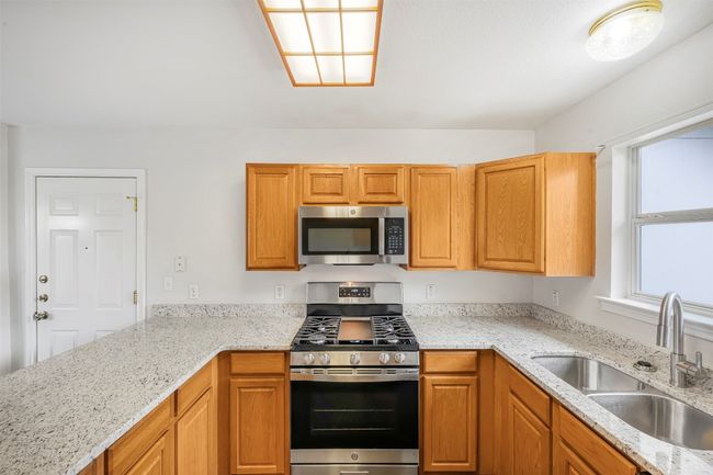 Kitchen featuring stainless steel appliances, light stone counters, and brown cabinets | Image 14