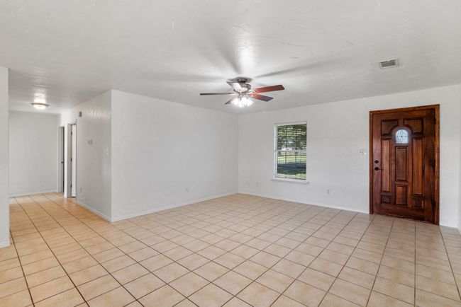 Empty room featuring ceiling fan and light tile patterned floors | Image 12