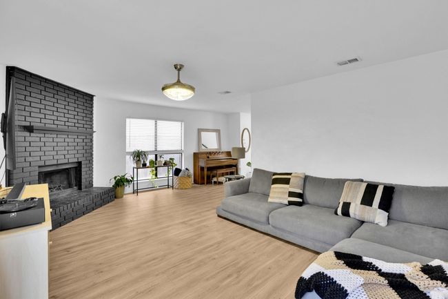 Living area with wood finished floors and a brick fireplace | Image 6