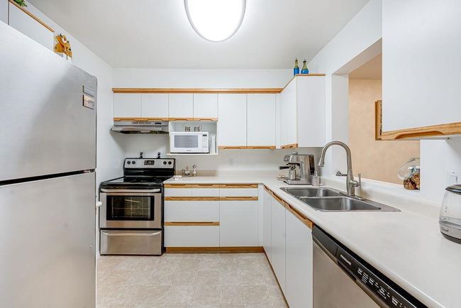 Kitchen with appliances with stainless steel finishes, under cabinet range hood, a sink, and light countertops | Image 29