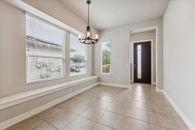Unfurnished dining area with a chandelier, light tile patterned floors, and baseboards | Image 21