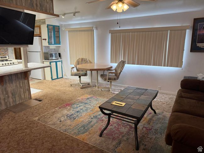 Carpeted living area featuring ceiling fan and rail lighting | Image 5