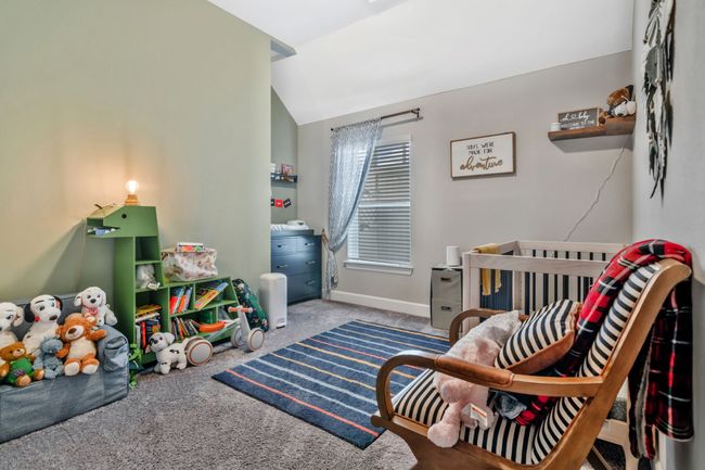 Bedroom with carpet flooring, lofted ceiling, and a crib | Image 23