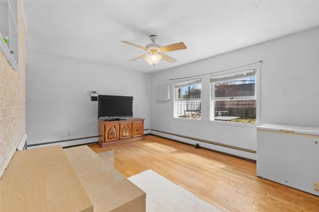 Unfurnished room featuring a baseboard radiator, a fireplace, wood finished floors, and a ceiling fan | Image 17