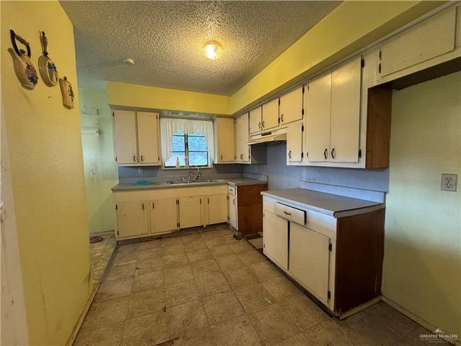Kitchen featuring a textured ceiling, a sink, and baseboards | Image 13