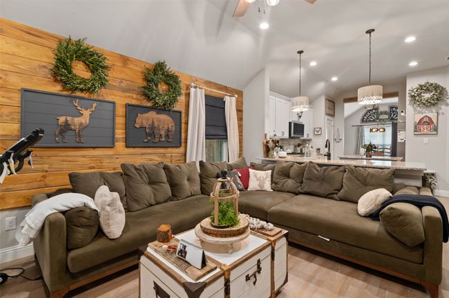 Living area featuring light wood-style floors, recessed lighting, ceiling fan, wood walls, and lofted ceiling | Image 11