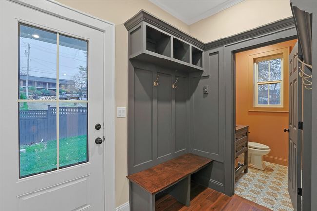 Mudroom off of side entrance, with coat closet, bench and raised panel accent wall. | Image 20