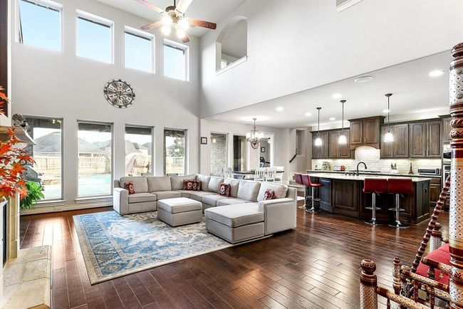 This expansive living room features high ceilings, showcasing open views to the foyer and the open balcony above. This design enhances the sense of openness and connectivity throughout the home, creating a seamless flow between the main living spaces and adding to the overall spacious, airy feel. | Image 19