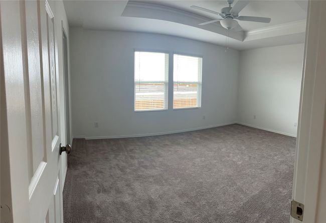 Carpeted empty room featuring a tray ceiling, ceiling fan, and baseboards | Image 13