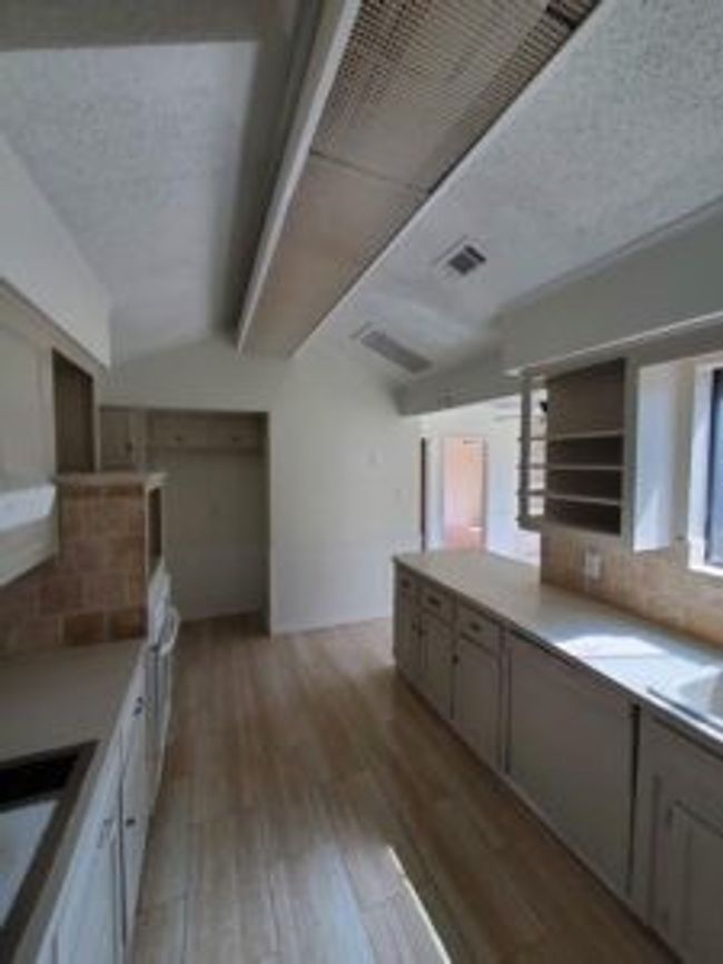 Kitchen with vaulted ceiling, wood finished floors, decorative backsplash, and light countertops | Image 18