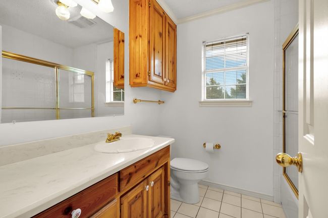 Second Floor guest bath with vanity, tile patterned floors, combined bath / shower with glass door, and crown molding | Image 18
