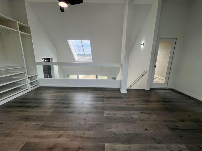 Unfurnished living room with a skylight, lofted ceiling, dark wood-type flooring, and ceiling fan | Image 19