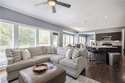 Living room with crown molding, a textured ceiling, dark hardwood / wood-style floors, and ceiling fan | Image 3