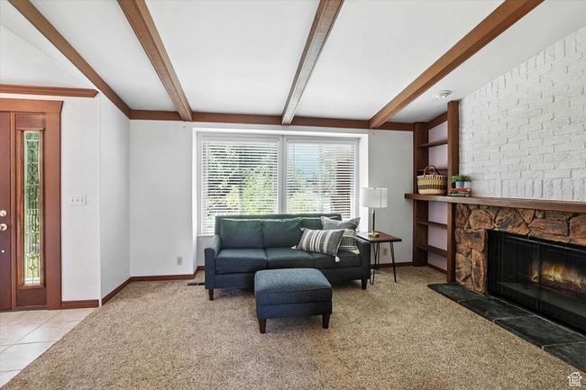 Carpeted living room with beam ceiling and a large fireplace | Image 6