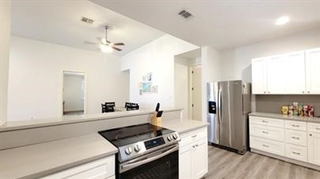 Kitchen with appliances with stainless steel finishes, light countertops, white cabinets, light wood finished floors, and ceiling fan | Image 10