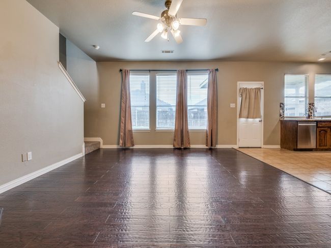 Unfurnished living room featuring a wealth of natural light, visible vents, a ceiling fan, and baseboards | Image 5