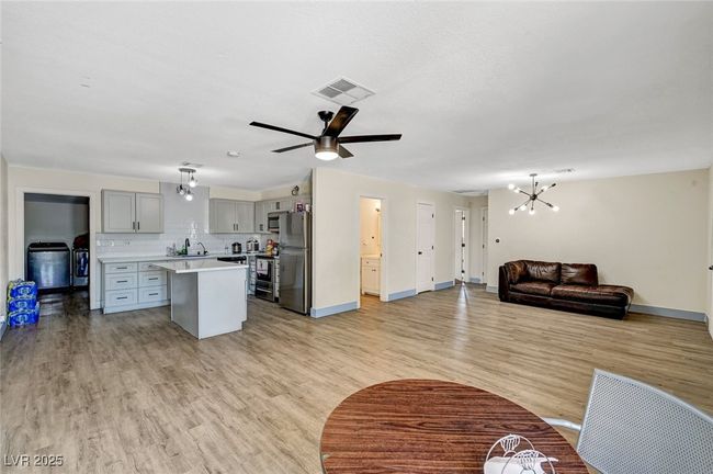 Kitchen with gray cabinetry, stainless steel appliances, light countertops, a chandelier, and open floor plan | Image 12
