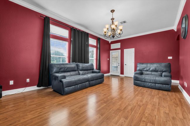 Living area featuring a chandelier, crown molding, wood finished floors, and baseboards | Image 12