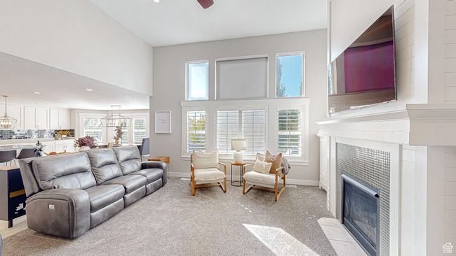 Living area featuring baseboards, a fireplace, a high ceiling, and light colored carpet | Image 10