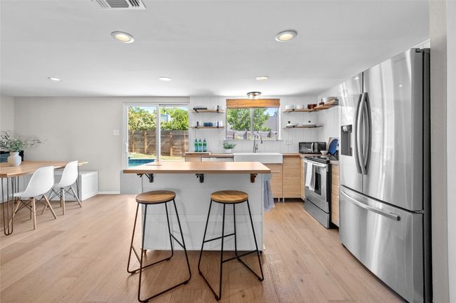 Updated in 2023 - the custom kitchen features open shelves, butcher block countertops and a breakfast bar | Image 9