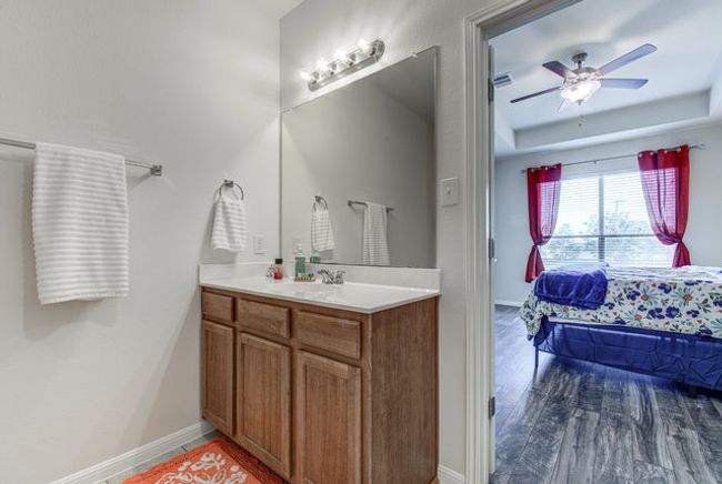 Bathroom with vanity, baseboards, a ceiling fan, a tray ceiling, and wood finished floors | Image 10